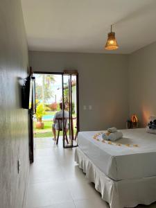 a bedroom with a bed and a person looking out the door at Pousada San Giovanni in Japaratinga +74 photos