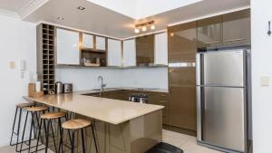 a kitchen with a stainless steel refrigerator and stools at Indulge In Ocean Views & Luxury! in Woorim