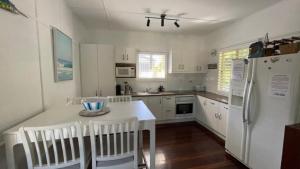 Una cocina con gabinetes blancos y un refrigerador blanco. en Stay Salty on Bribie Island, en Woorim