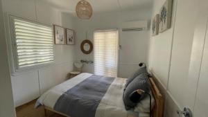 un dormitorio con una cama y una ventana en Stay Salty on Bribie Island, en Woorim