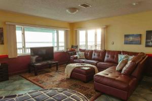 sala de estar con sofá de cuero marrón y TV en Admiral Suite, en St. Augustine