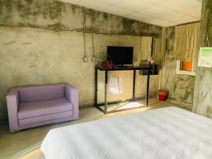 1 dormitorio con sofá púrpura y TV en ปานีวิลล์ รีสอร์ต, en Ban Wang Takhrai