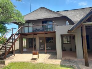 una casa con una gran terraza y una escalera en Matori Lodge, en Modimolle