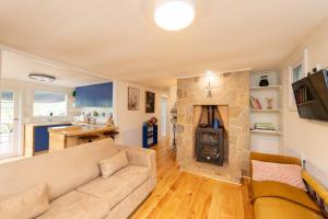 a living room with a couch and a stone fireplace at Delphi, Adelaide Hills Garden BnB in Mylor