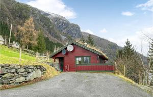 a red house on a hill with a stone wall at Stunning Home In Lauvstad With Wifi And 2 Bedrooms in Lauvstad