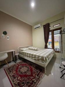 a bedroom with a bed with a rug and a window at Spacious 2BR Home - 14 Min from Sukabumi city Centre by Sakura in Sukaraja