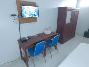 a desk with two blue chairs and a television on a wall at A & A Residence Syariah in Sukarami