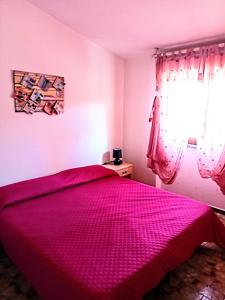 een slaapkamer met een roze bed en een raam bij Casa freogan in Castelsardo