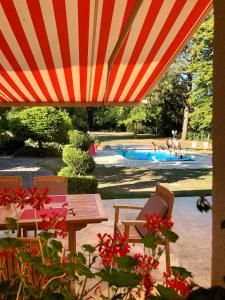 een tafel en stoelen onder een parasol met een zwembad bij Le Jardin de Fresnes in Fresnes-en-Woëvre