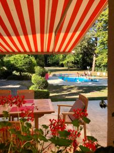 a table and chairs under an umbrella with a swimming pool at Le Jardin de Fresnes in Fresnes-en-Woëvre