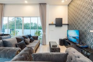 a living room with couches and a flat screen tv at Dara pool villa in Ban Bang Liang