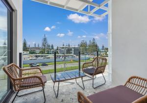 a patio with three chairs and a table on a balcony at Sunny Gold Coast Miami Getaway in Gold Coast