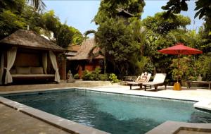 a woman sitting in a chair next to a swimming pool at Villa Varuna in Legian