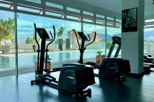 a gym with several treadmills and a swimming pool at Festival Walk homestay,13min to Tambun Lost World in Ipoh
