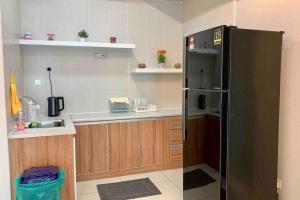 a kitchen with a black refrigerator and wooden cabinets at Festival Walk homestay,13min to Tambun Lost World in Ipoh