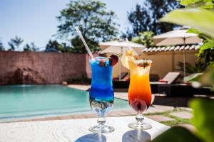 twee cocktails op een tafel naast een zwembad bij Golden Horse Hotel 
