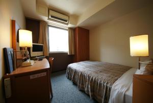 名古屋市にあるホテルランドマーク名古屋のベッド、デスク、コンピュータが備わるホテルルームです。