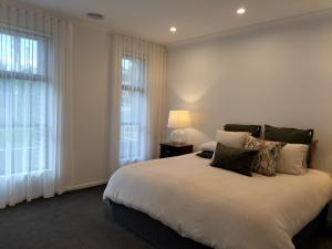 a bedroom with a bed with a lamp and windows at Harvey's Haven in Castlemaine +13 photos