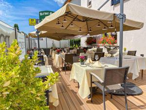 a restaurant with tables and chairs and an umbrella at Hotel Re'ser Stuff in Roeser