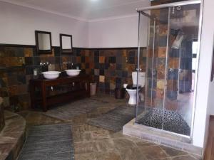 a bathroom with a shower and two sinks and a toilet at Langstrand Beach House in Langstrand