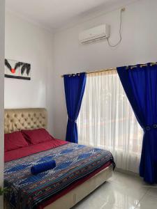 Sama sama Karimunjawa في كاريمونجاوا: غرفة نوم بسرير والستائر الزرقاء ونافذة