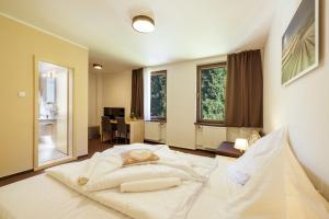 a large white bed in a room with windows at Lopušná dolina Resort in Vysoké Tatry