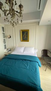 a bedroom with a blue bed with a chandelier at Alexa Meisterstadt pollux habibie in Batam Center
