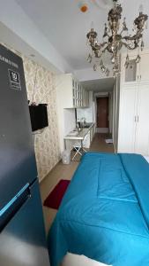 a bedroom with a blue bed and a kitchen at Alexa Meisterstadt pollux habibie in Batam Center