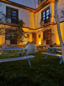 a group of picnic tables in front of a building at Kusadasi Sezgins Boutique Rooms in Kuşadası
