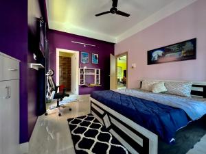 a bedroom with purple walls and a bed and a chair at Three Little Birds Homestay in Guwahati