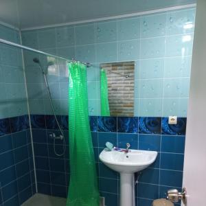 a bathroom with a green shower curtain and a sink at Guest house na Myasnikova Diamond in Novy Afon