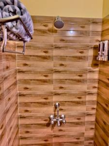 a bathroom with a shower with a wooden floor at Three Little Birds Homestay in Guwahati