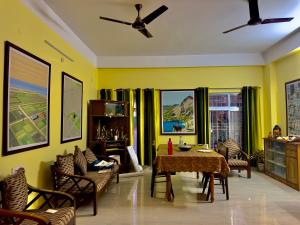 salon z żółtymi ścianami, stołem i krzesłami w obiekcie Three Little Birds Homestay w mieście Guwahati