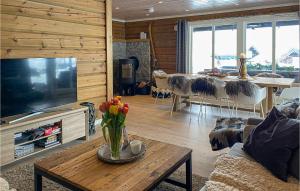 a living room with a television and a table with flowers at Lovely Home In Sykkylven With House A Panoramic View in Sykkylven