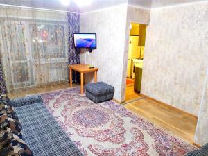 sala de estar con TV y mesa con alfombra. en 3-х комнатная квартира район ЖД вокзала, en Kostanái