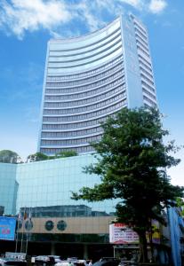 a tall building with a tree in front of it at Ocean Hotel Guangzhou-Free Shuttle Bus to Canton Fair in Guangzhou