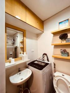 La salle de bains est pourvue d'un lavabo, de toilettes et d'un miroir. dans l'établissement Condominium at Spring Residences near Airport, à Manille
