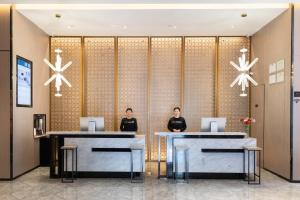duas mulheres de pé na recepção no átrio em Atour Hotel Hefei Changjiang Road em Hefei