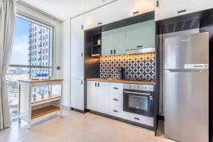 a kitchen with white cabinets and a stainless steel refrigerator at Host and Stay - Collective tower 1, Dubai Hills Estate in Dubai