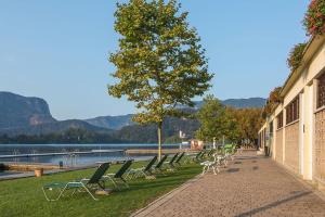 una fila de sillas sentadas en una acera junto a un lago en Roki Bled, en Bled