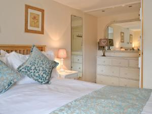 a bedroom with a bed and a dresser and a mirror at Dolls Cottage in Bourton on the Water