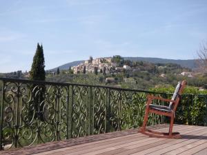 una sedia in legno seduta su un balcone con un castello sullo sfondo di Pool House Matisse in large park with heated pool a Châteauneuf Altre 37 foto