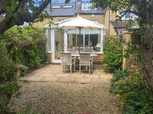 a patio with a table and chairs and an umbrella at Dolls Cottage in Bourton on the Water