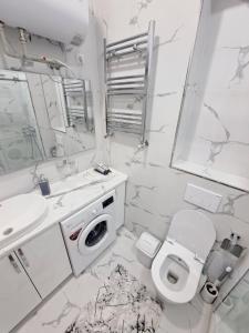 a white bathroom with a toilet and a sink at Apartment in City Center in Dushanbe