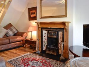a living room with a fireplace and a couch at Dolls Cottage in Bourton on the Water