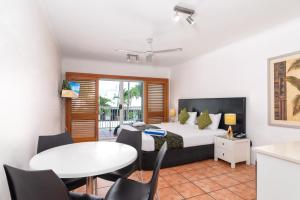 um quarto com uma cama, uma mesa e cadeiras em Paradise On The Beach Resort em Palm Cove
