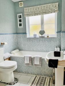 ein Badezimmer mit einer Badewanne, einem WC und einem Waschbecken in der Unterkunft Woodbriar in Conwy