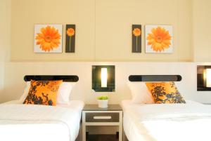 2 Betten in einem Zimmer mit Blumen an der Wand in der Unterkunft The Inn Saladaeng in Bangkok