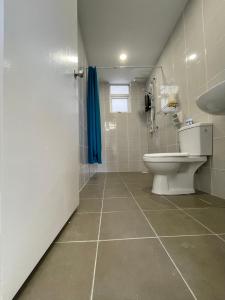 a bathroom with a toilet and a blue shower curtain at Bayu Andaman KL Centre in Kuala Lumpur +3 photos