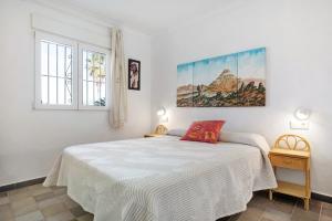 a bedroom with a white bed and a painting on the wall at Casa Vistas al Mar Bolonia in Tarifa